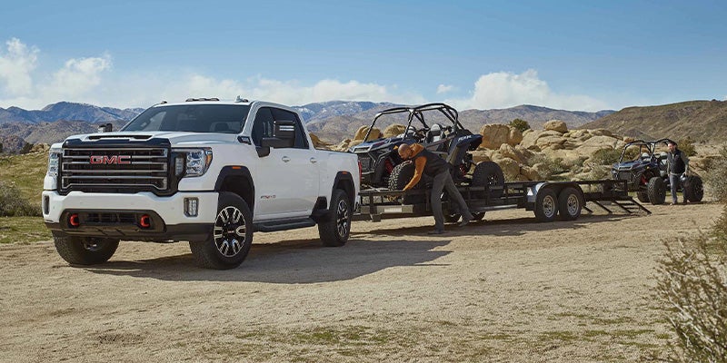 A 2022 GMC Sierra 2500HD towing a large trailer on a rural road.